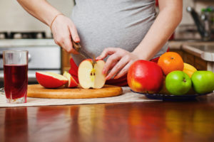 pregnant woman cutting apple 