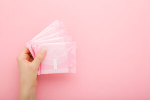 girl holding menstrual pads on pink background 