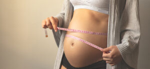 Pregnant woman holding tape measure. 