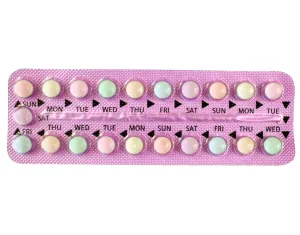 A pink blister pack of birth control pills with four rows of various pastel-colored pills labeled with days of the week.
